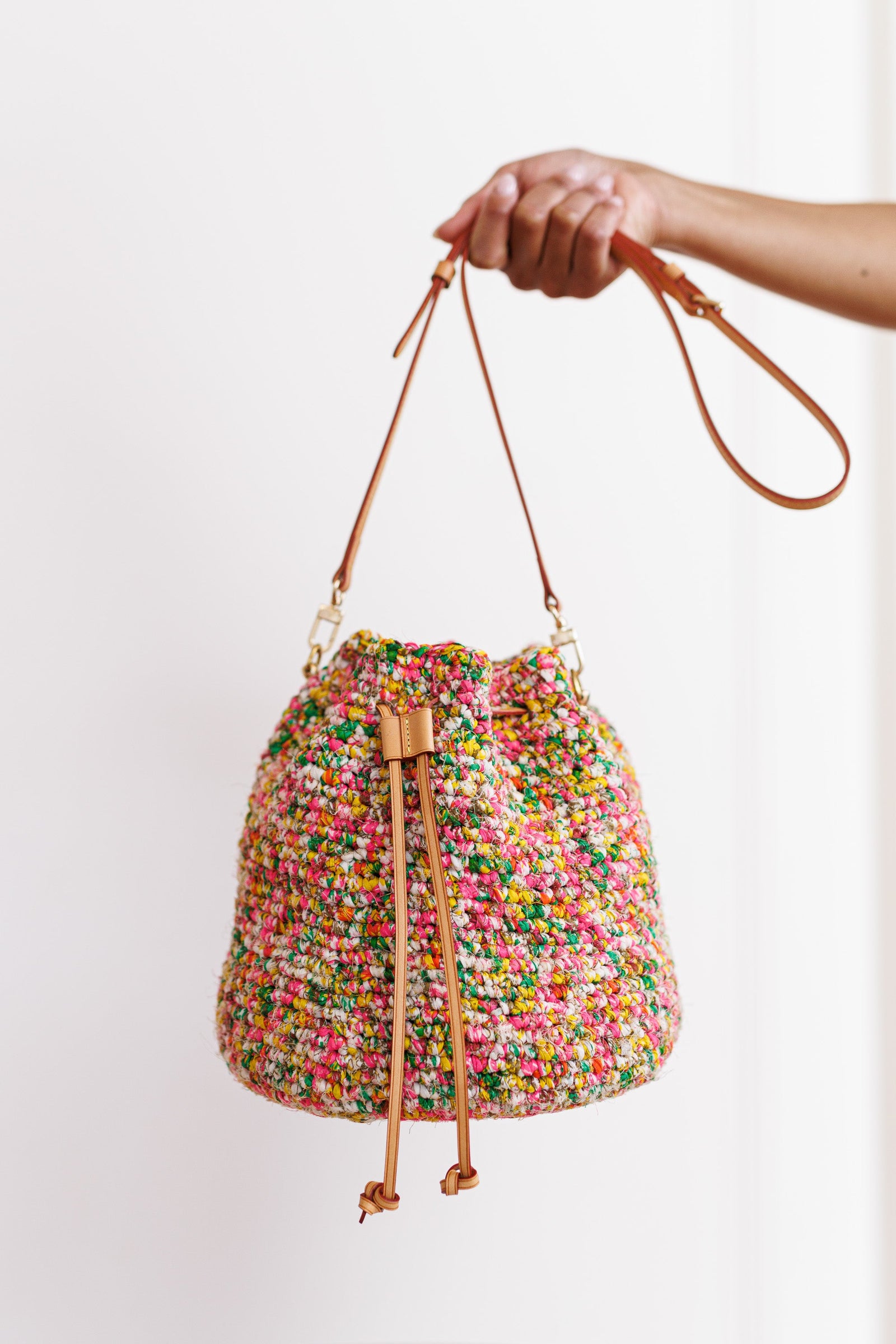 Model using one hand to hold bag out in front of blank, white wall