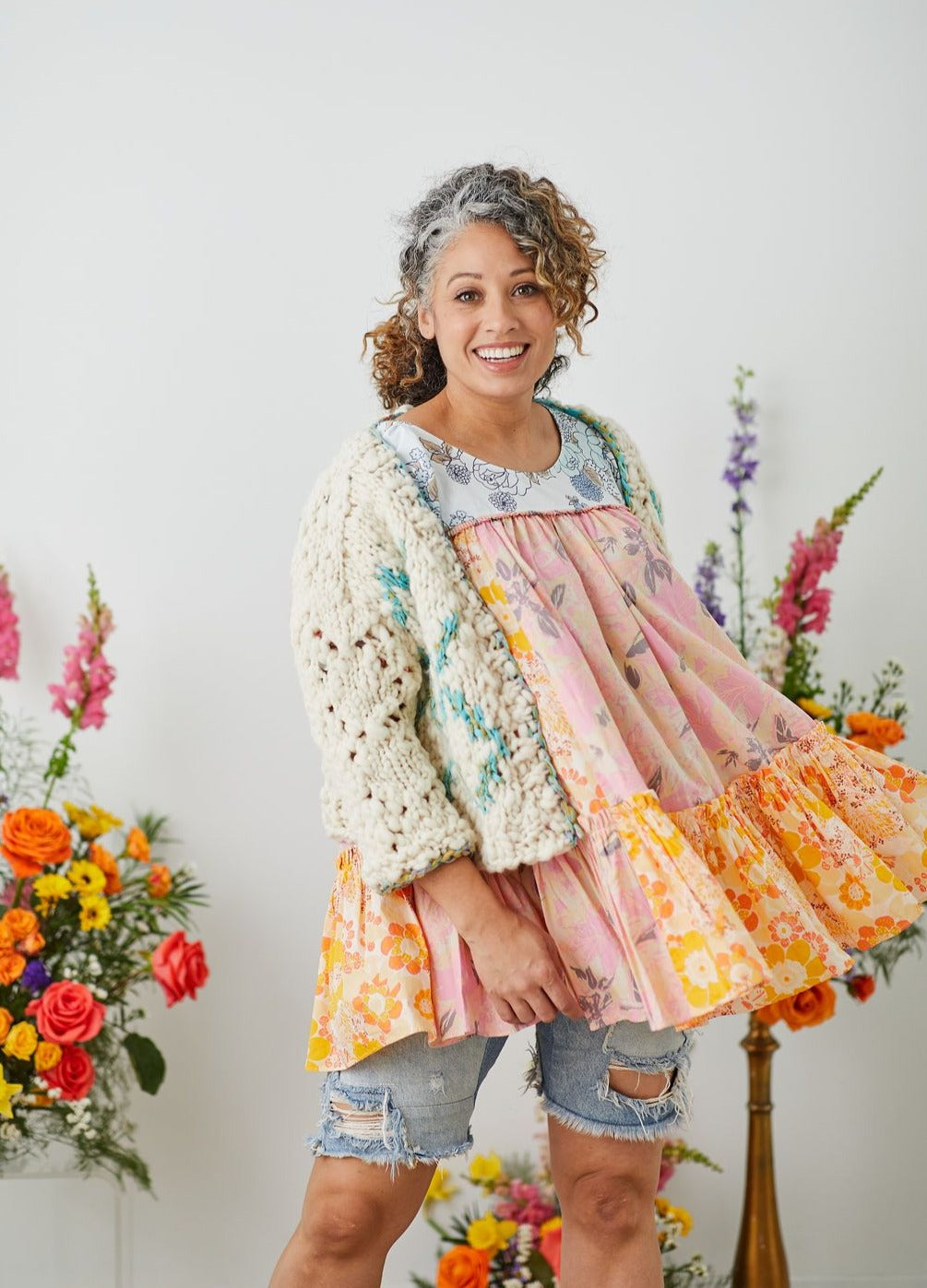 Model wearing High Fives Cardigan over patchwork flowy top and ripped jean shorts