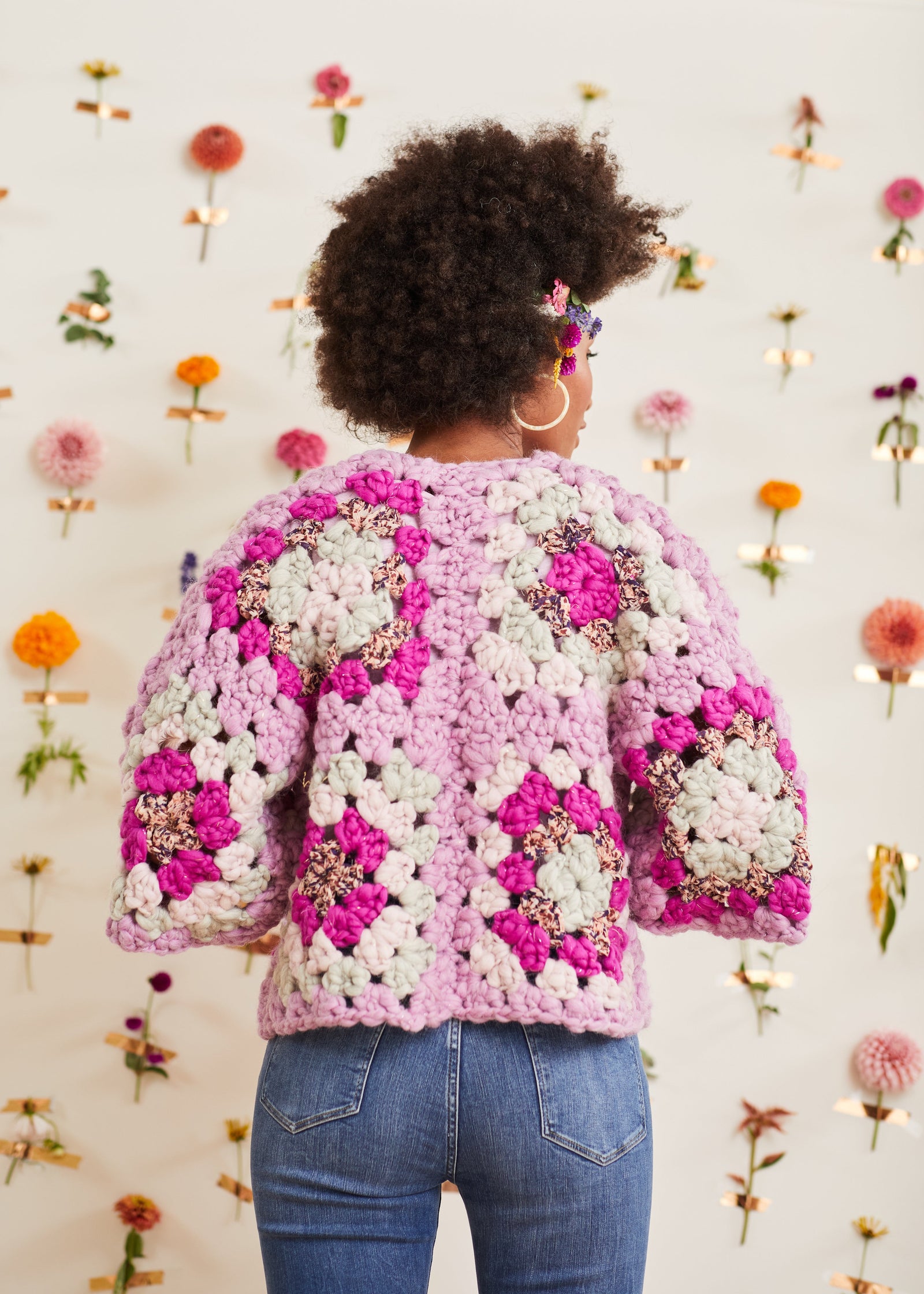 Model, with arms bent, shows back of lavender crochet cardigan