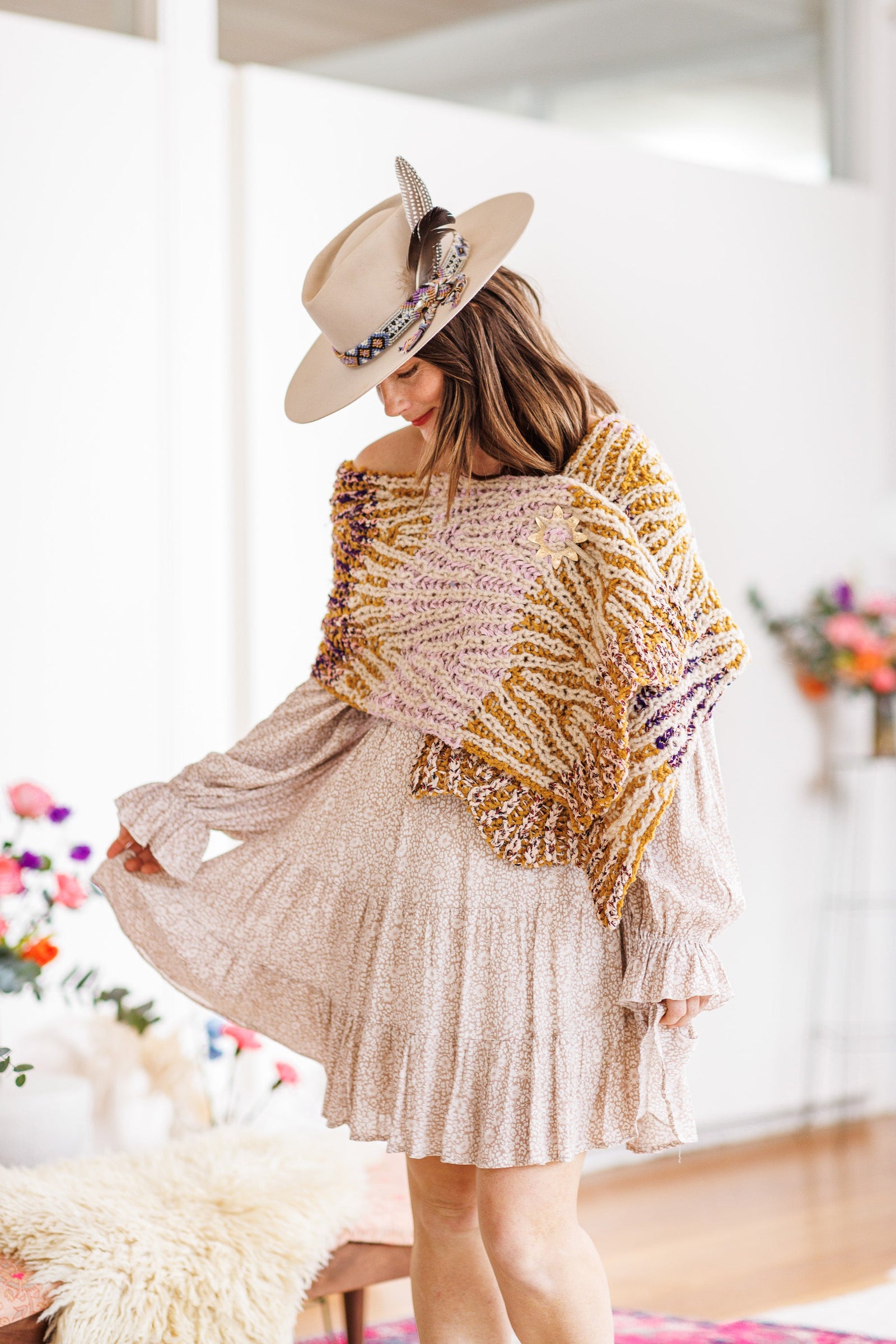 Model in hat and dress wears knit wrap help closed with brass shawl pin