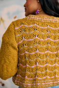 Person wearing a mustard yellow and pink patterned sweater against a blurred background