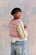 Woman wearing a handknit sweater against a soft, multicolored background