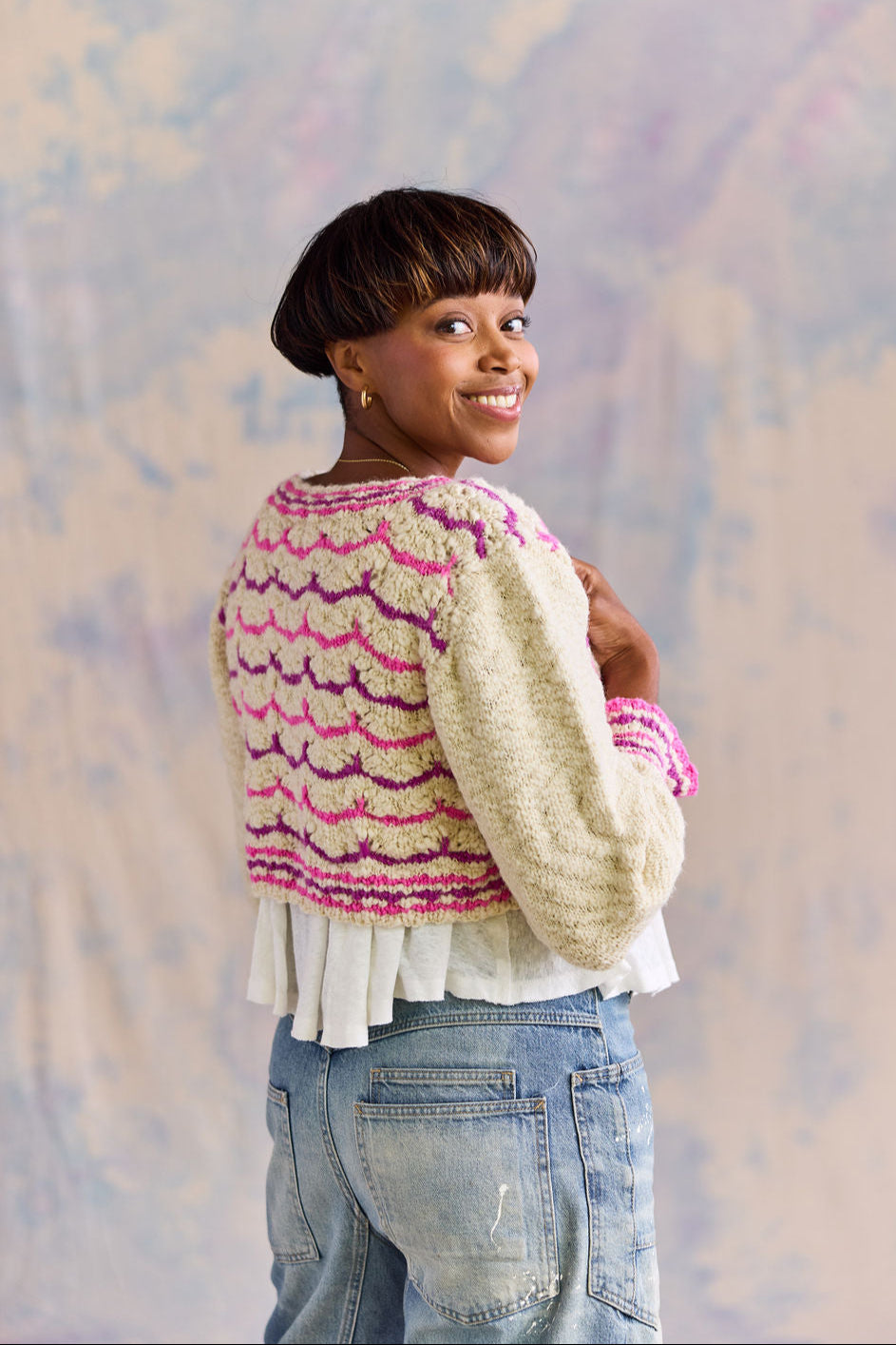 Woman wearing a handknit sweater against a soft, multicolored background