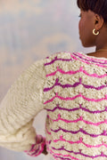 Person wearing a textured sweater with pink and purple pattern against a blurred background