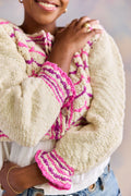 Person wearing a cream-colored cardigan with pink and purple patterned sleeves and cuffs.