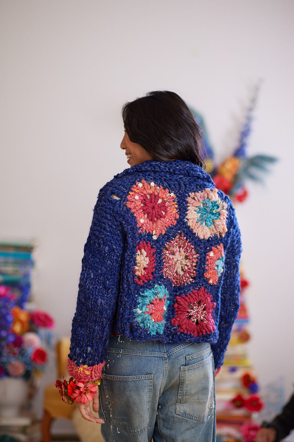 Model displaying back view of crochet and knit cardigan featuring hexagon granny squares