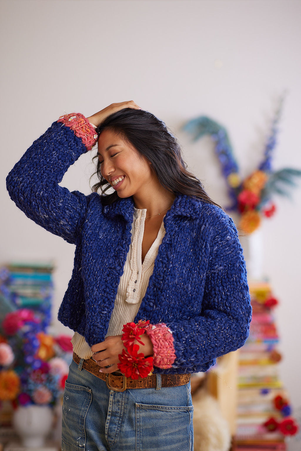 Smiling model has arm raised wearing ink blue wool cardigan with collar