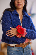 Models arms are crossed in front of body displaying sleeves  of wool cardigan with cuff ribbing detail and flower bracelet