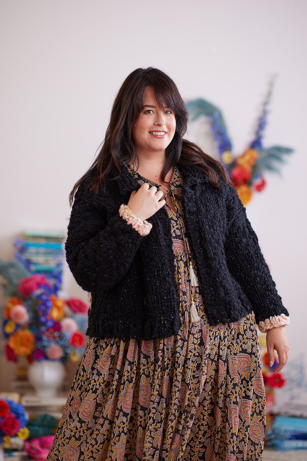 Smiling model holding one side of the cardigan collar 