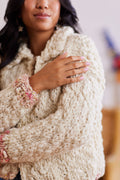 Close up of pink and cream ribbed cuff with daisy detail on cream kit and crochet cardigan with collar