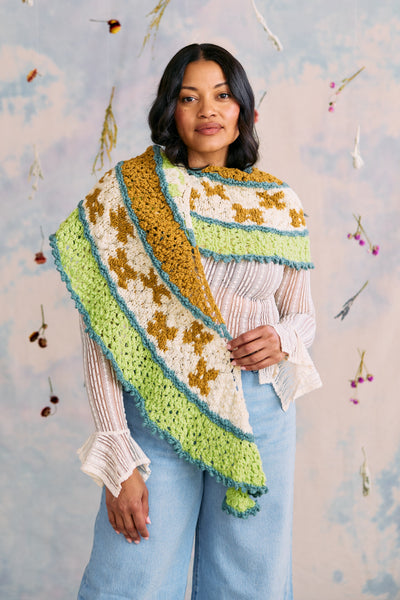 Woman wearing a colorful crocheted shawl against a floral background