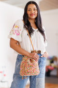Model wearing a multicolored, cotton crochet bucket bag with shoulder strap