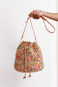 Model using one hand to hold bag out in front of blank, white wall