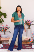 Model bending arm in front of ice green, boucle, knit cardigan