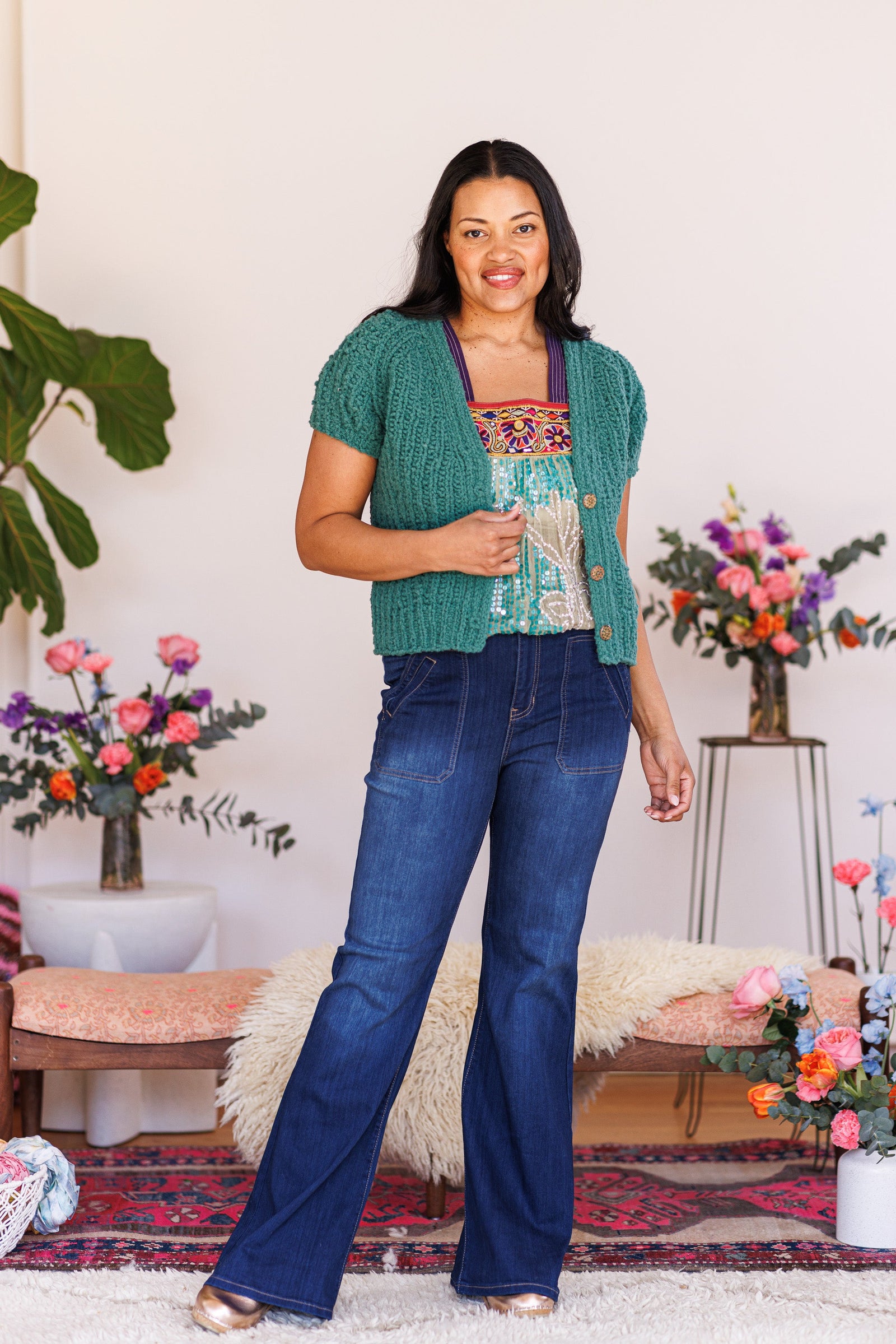 Model bending arm in front of ice green, boucle, knit cardigan