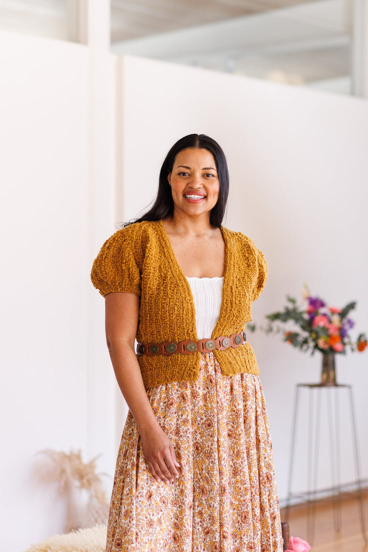 Smiling model wearing short puff sleeve marigold cardi belted at waist