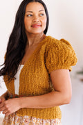 Close-up of model looking over shoulder wearing short puff sleeve knit cardi