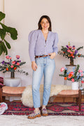Smiling model wearing long-sleeve knit cardigan with one hand in pocket of denim jeans