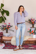 Model wearing puff-sleeve, V-neck, periwinkle, boucle, knit cardi with one hand reaching to tuck hair behind ear 