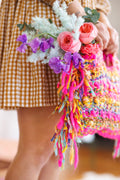 Close-up of yarn fringe along the side of handbag with flowers popping out of the top of bag