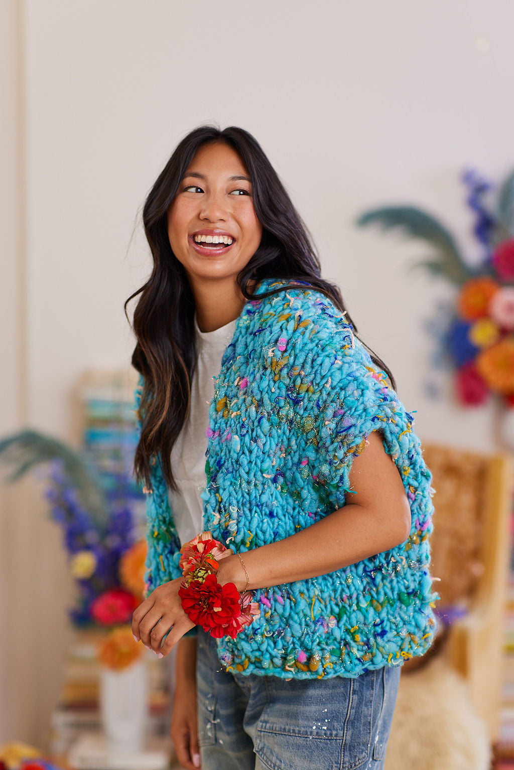 Model smiling wearing under the sea blue Happy Dance Cardi and a flower bracelet