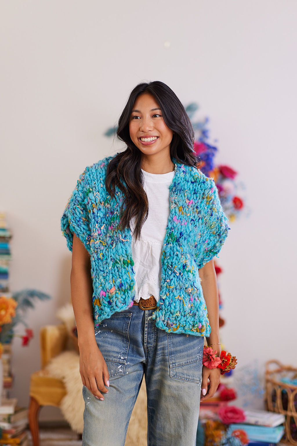 Smiling Model wearing white shirt, denim jeans, brown belt, and the Happy Dance knit cardigan