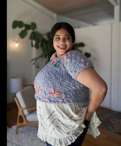 Model standing while posing wearing the sweater