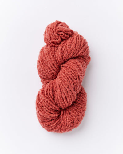 A skein of brushed boucle yarn in a brick red color