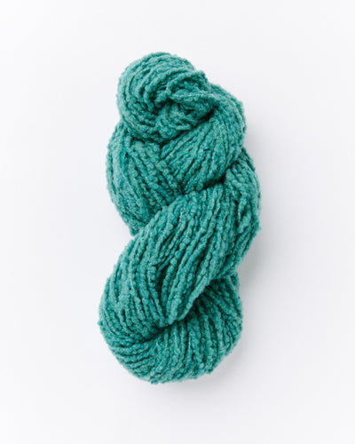 A skein of brushed boucle yarn in a pine green color with blue undertones