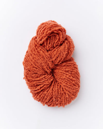 A skein of brushed boucle yarn in a burnt orange color.