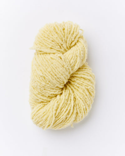 A skein of brushed boucle yarn in a butter yellow color.