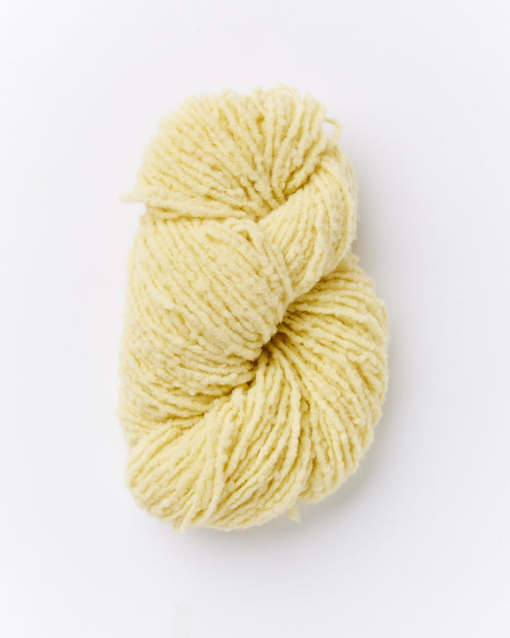 A skein of brushed boucle yarn in a butter yellow color.