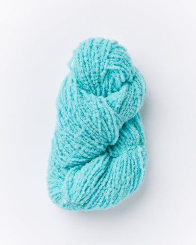 A skein of brushed boucle yarn in a bright aqua blue color.