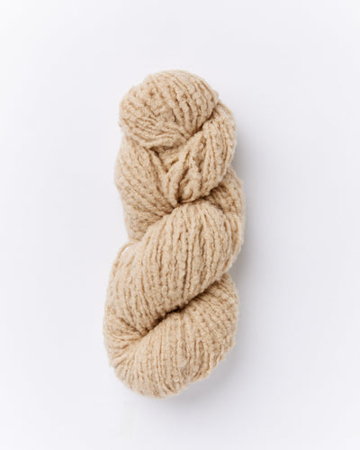 A skein of brushed boucle yarn in a light khaki tan color