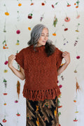 Model standing in front of a flower backdrop showing the sleeves of the Provence Poncho