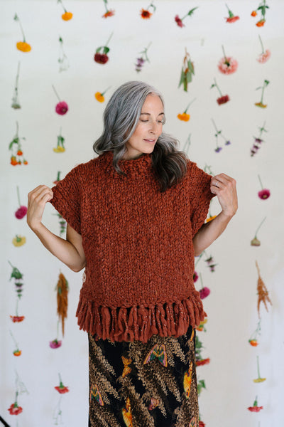 Model standing in front of a flower backdrop showing the sleeves of the Provence Poncho