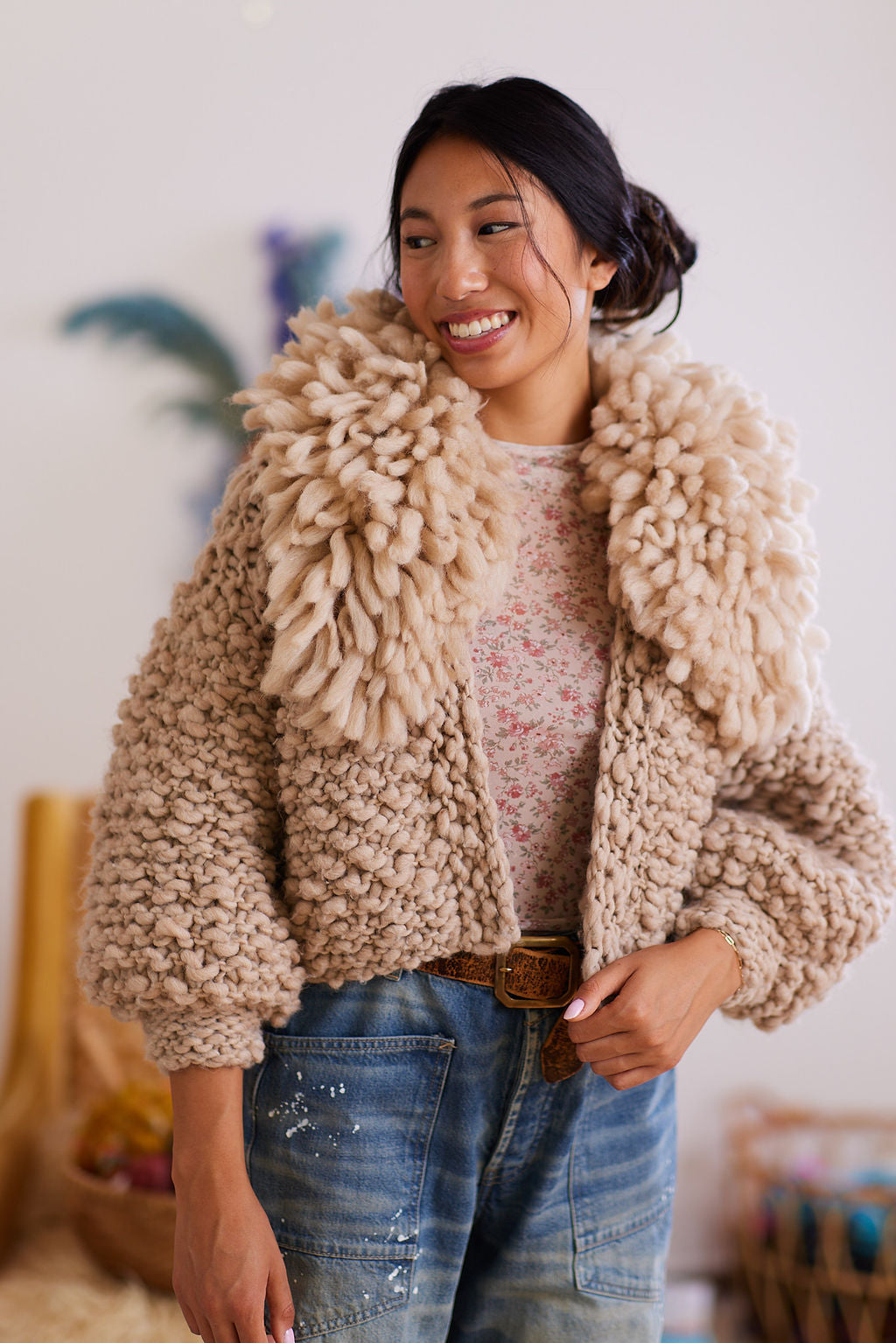 Smiling model wearing wool cardigan with matching fringe color