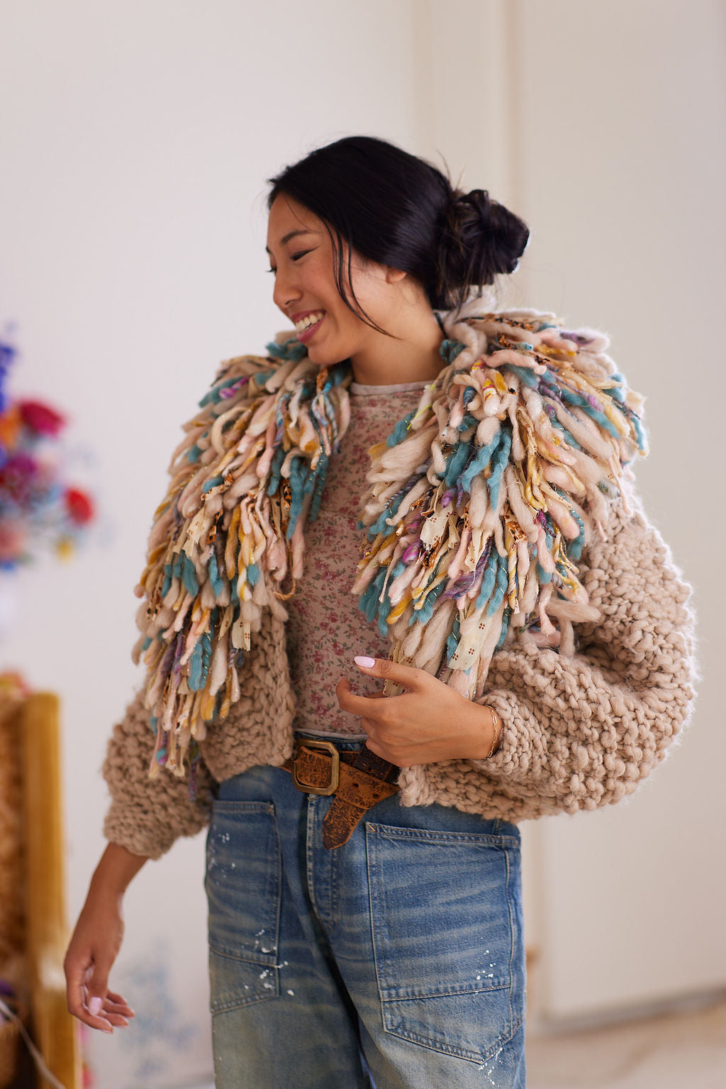 Wool cardigan with multicolored fringe collar worn with floral top and denim jeans