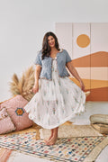Woman wearing a white dress with flowers and a short sleeve light blue cardigan