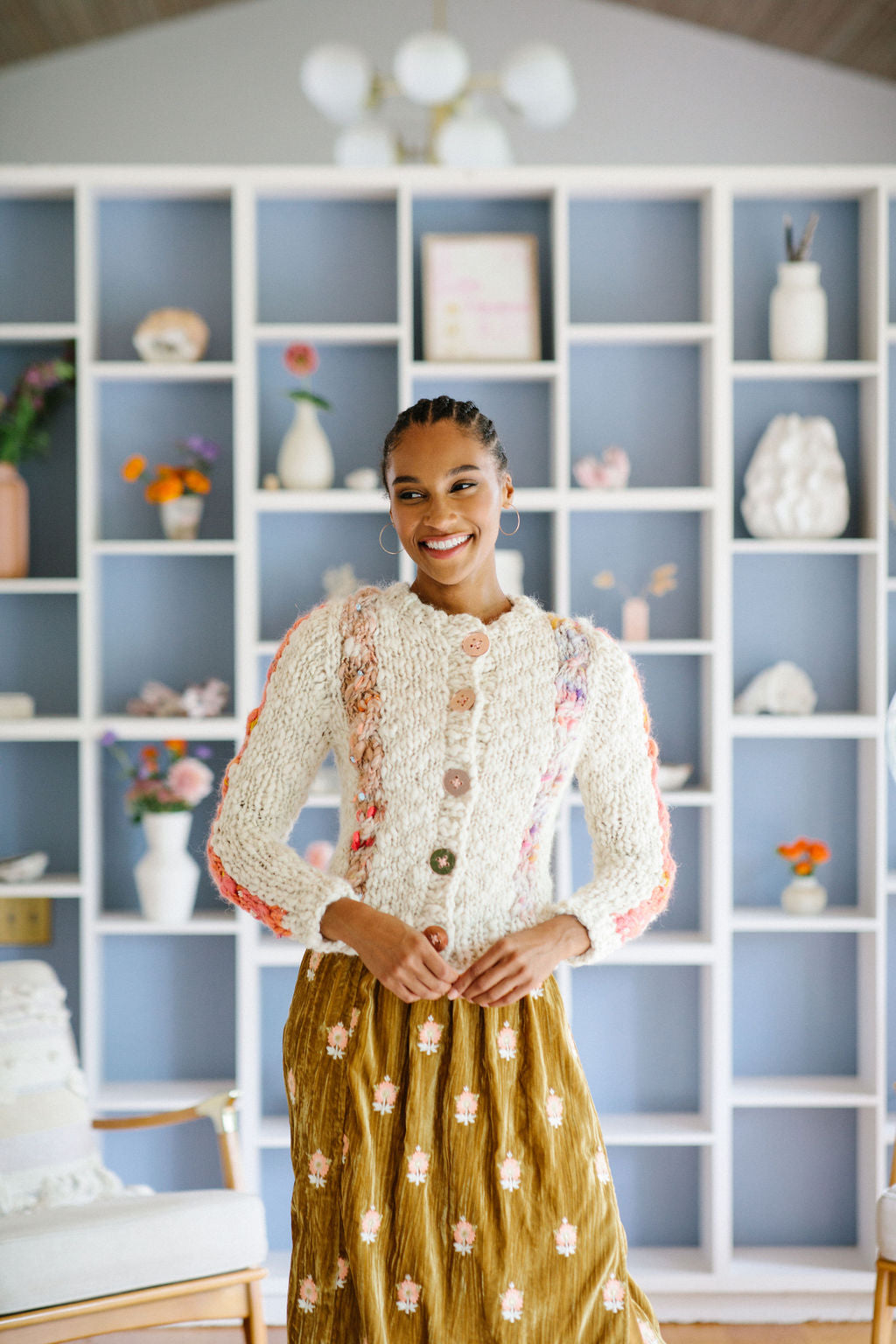 Woman wears a buttoned up cabled cardigan over a dress