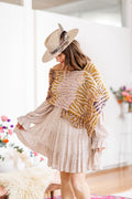 Model in hat and dress wears knit wrap help closed with brass shawl pin