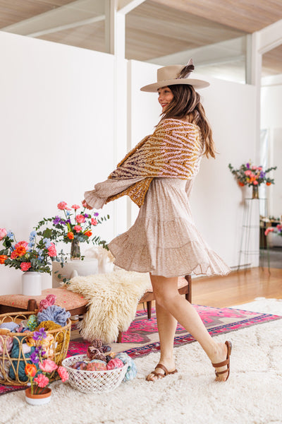 Model turns to display repeating lace pattern on multicolor knit wrap