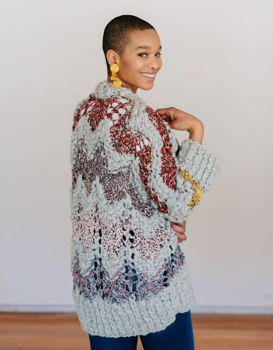Model smiling looking over shoulder wearing a sweater.