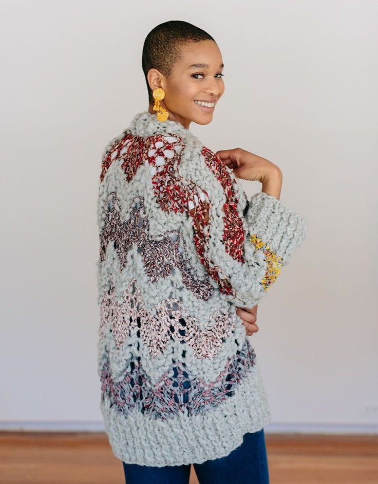Model smiling looking over shoulder wearing a sweater.