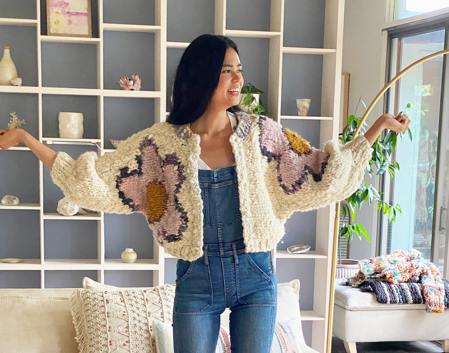 Model smiling, holding arms out showing flowers on cardi.