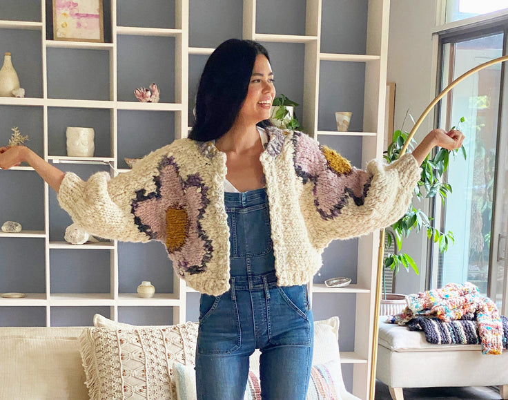 Model smiling, holding arms out showing flowers on cardi.