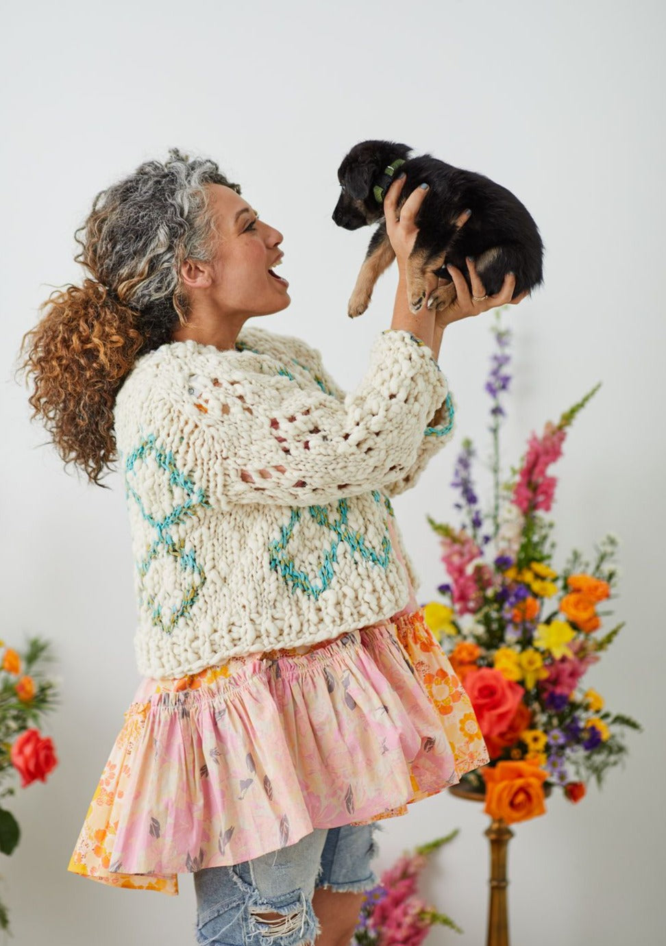 Model wearing High Fives Cardi holding a little black and tan puppy
